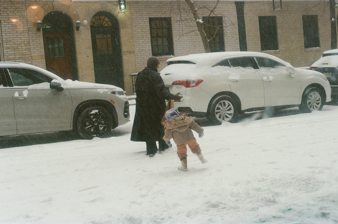 Adult and child walking down a snowy sidewalk