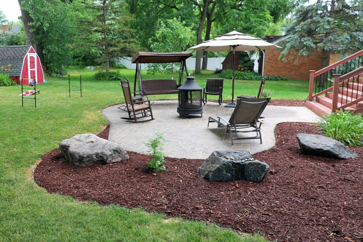 Backyard patio with freshly mulched beds and boulders