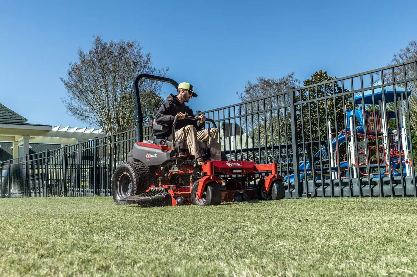 Zero-turn mower working along a playground fence at a school in Sheboygan County