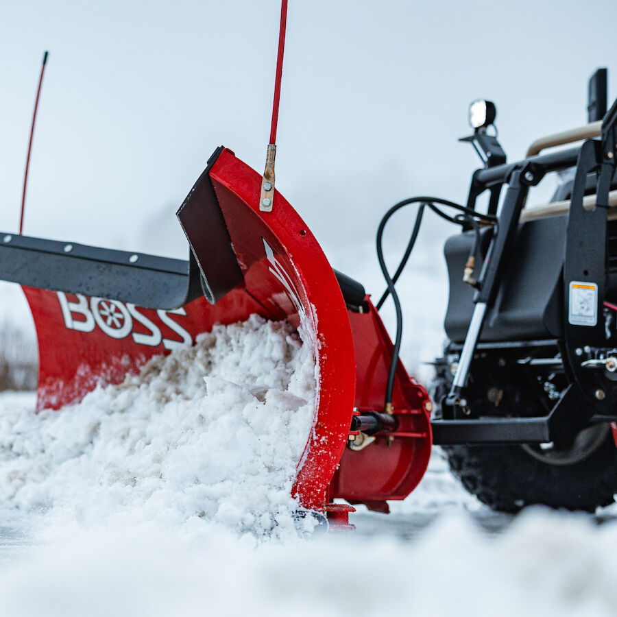 Red Boss plow blade pushing snow off a driveway