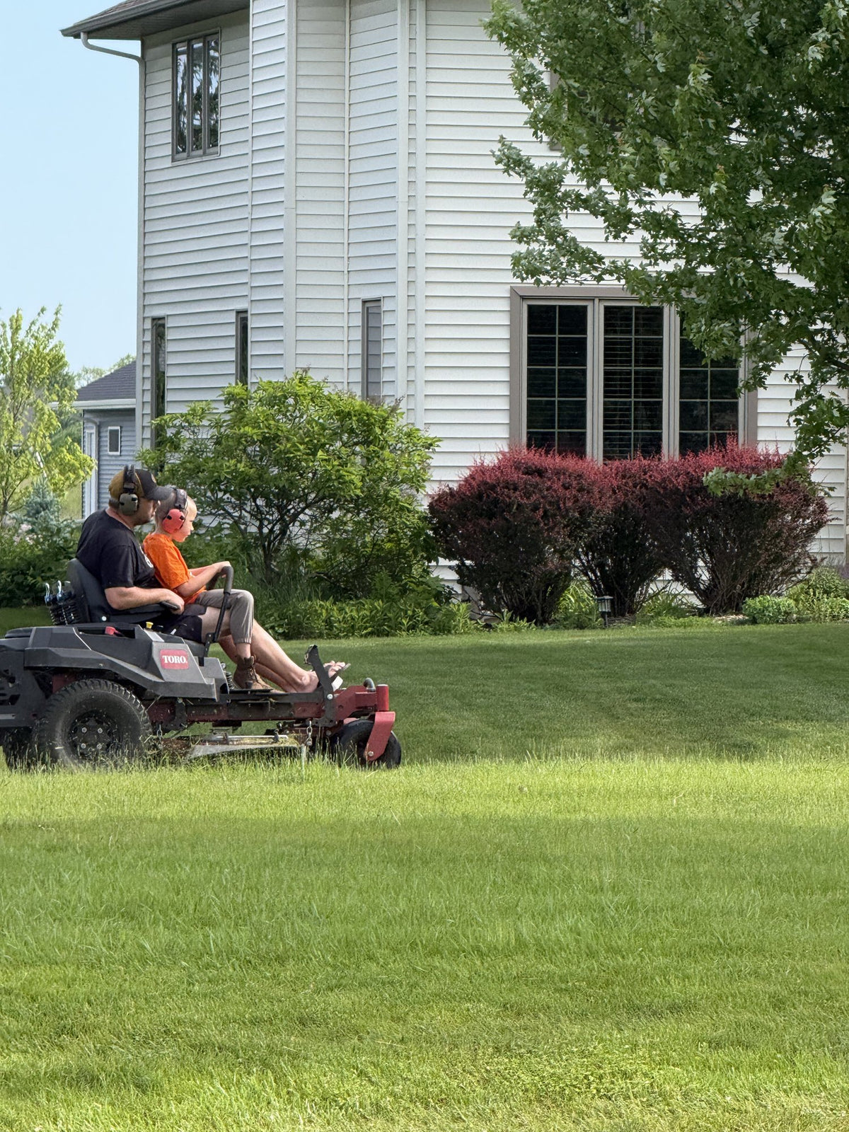 Carl and Mack mowing a Sheboygan front lawn together on the zero-turn