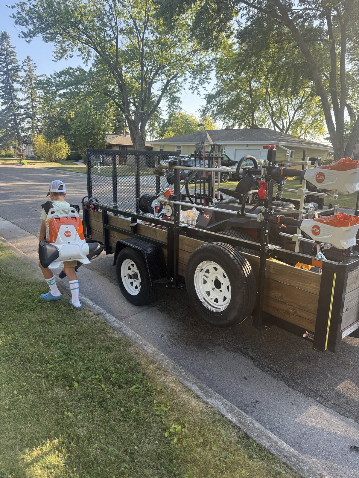 Sunny Stripes Landscaping trailer loaded with a Toro zero-turn, STIHL trimmers and blowers on a job in Sheboygan County