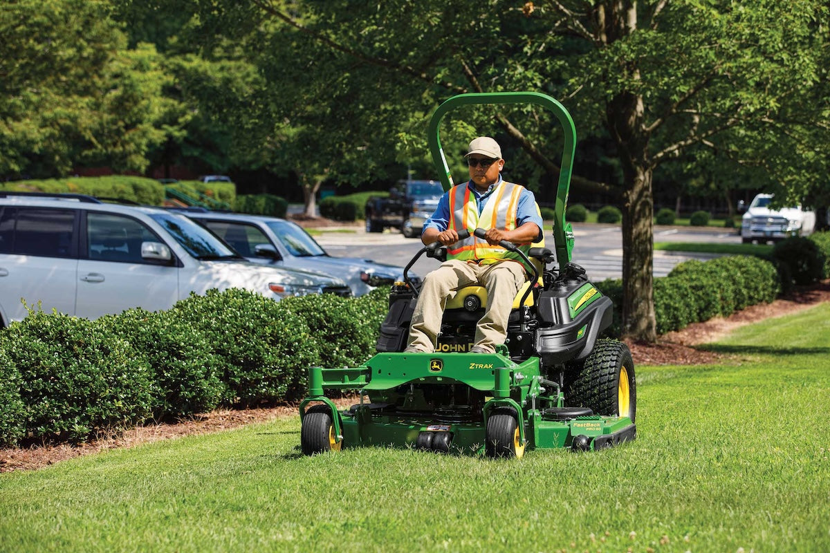 Zero-turn mower working along trimmed hedges at a commercial property