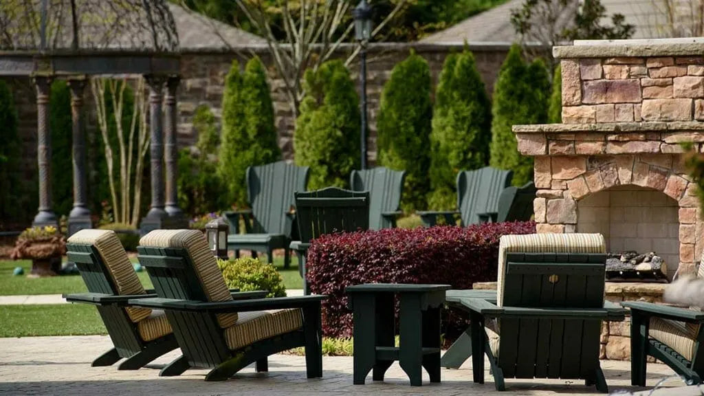 Courtyard patio with Adirondack chairs, trimmed hedges and a stone fireplace at a senior living community